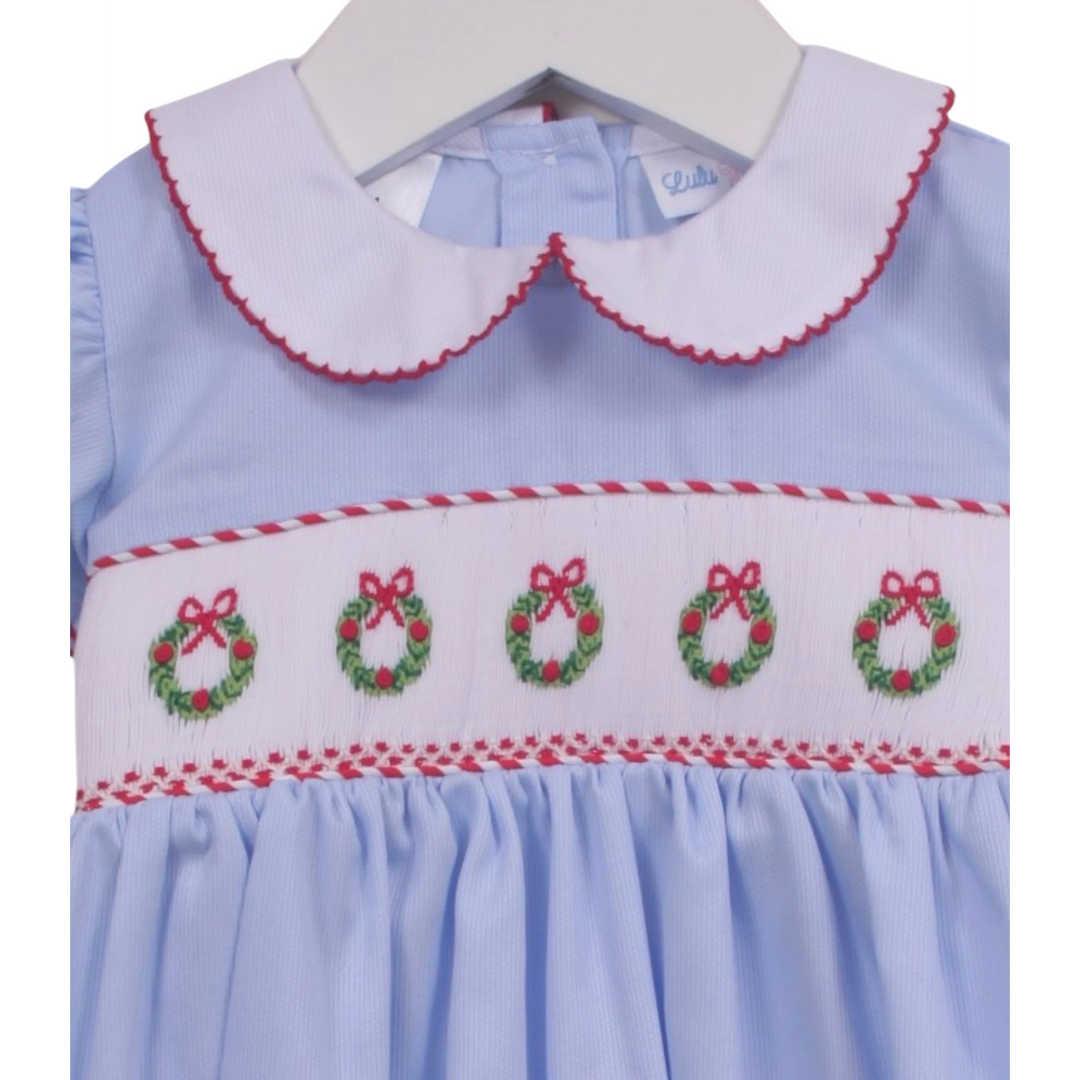 That Store blue girls bubble with smocked Christmas wreath embroidery, white peter pan collar, and red trim.