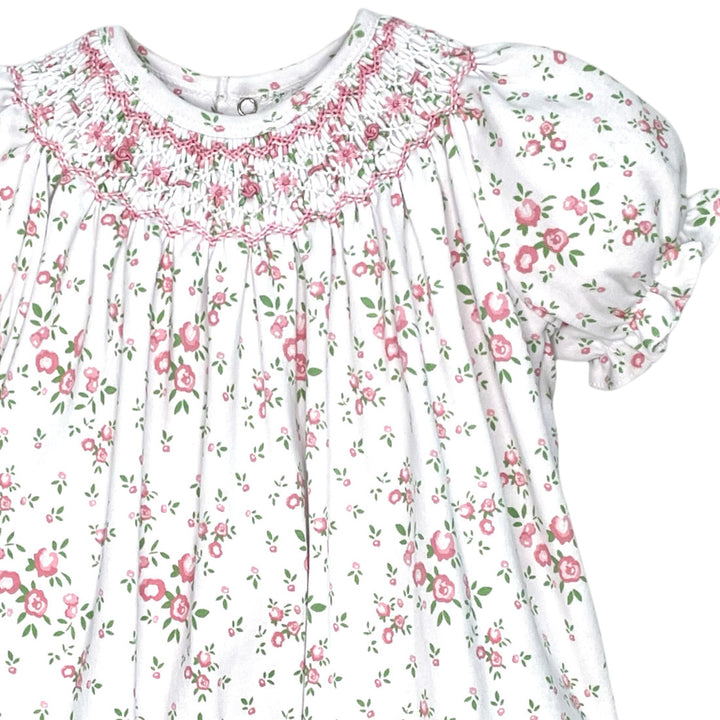 That Store smocked knit baby romper in white with pink and green floral print, puff sleeves, and vintage detailing.