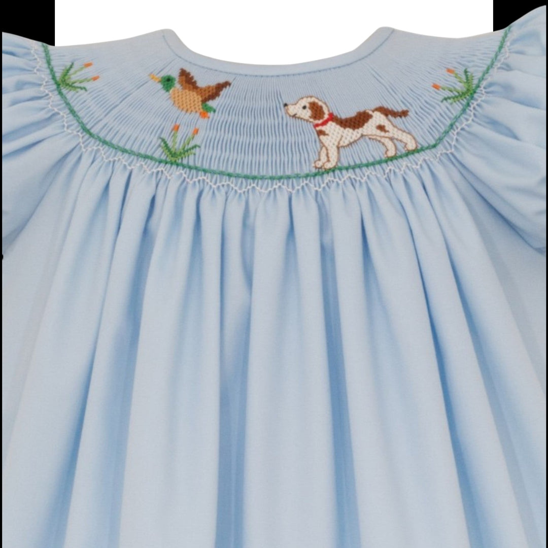 That Store light blue smocked bishop dress for girls featuring hand-embroidered hunting dog and mallard duck details.