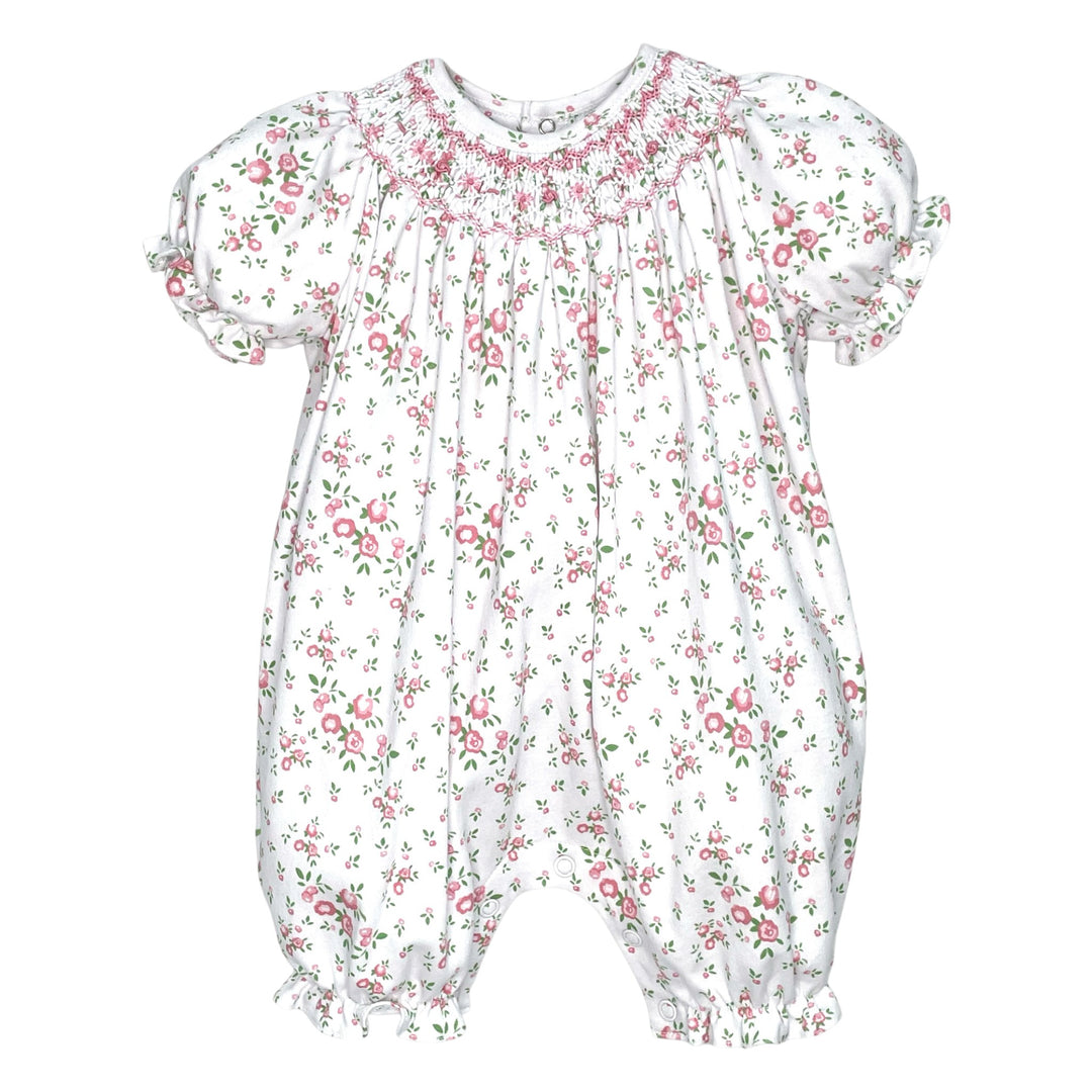 That Store pink floral knit baby romper with hand-stitched smocking, puff sleeves, and ruffled leg openings.