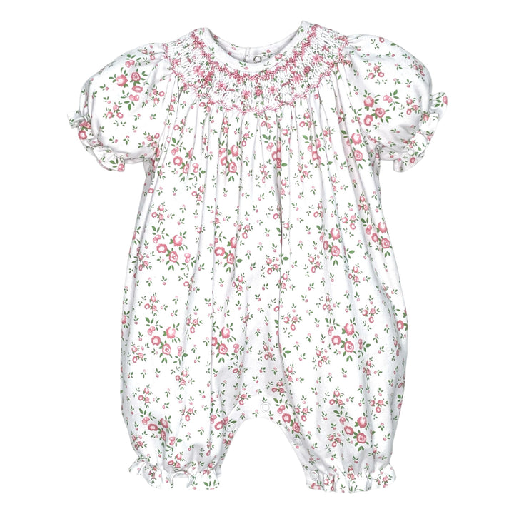 That Store pink floral knit baby romper with hand-stitched smocking, puff sleeves, and ruffled leg openings.
