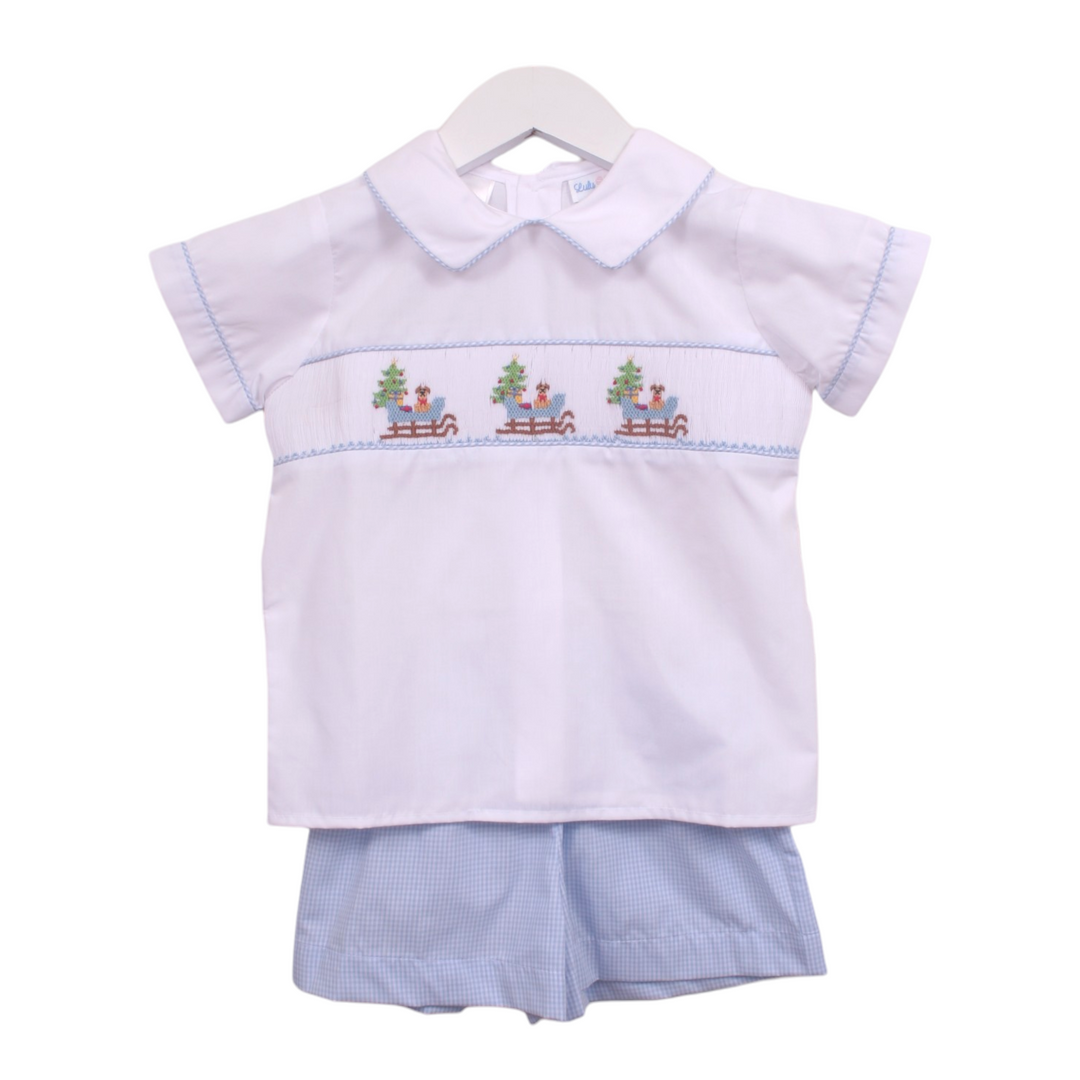 That Store boys short set featuring a white shirt with smocked puppy in a sleigh design and blue gingham shorts.