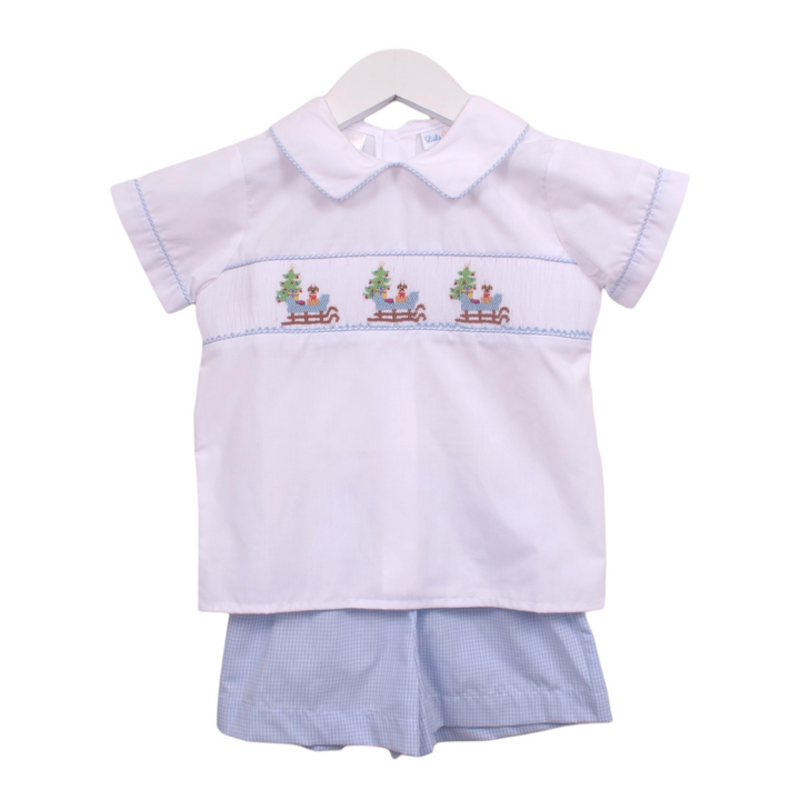 That Store boys short set featuring a white shirt with smocked puppy in a sleigh design and blue gingham shorts.