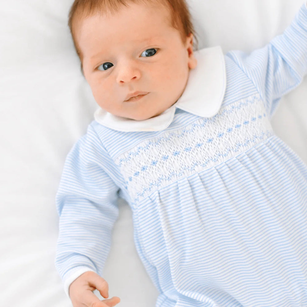 Newborn baby wearing a That Store light blue and white striped Pima cotton footie with hand-smocked chest and collar.