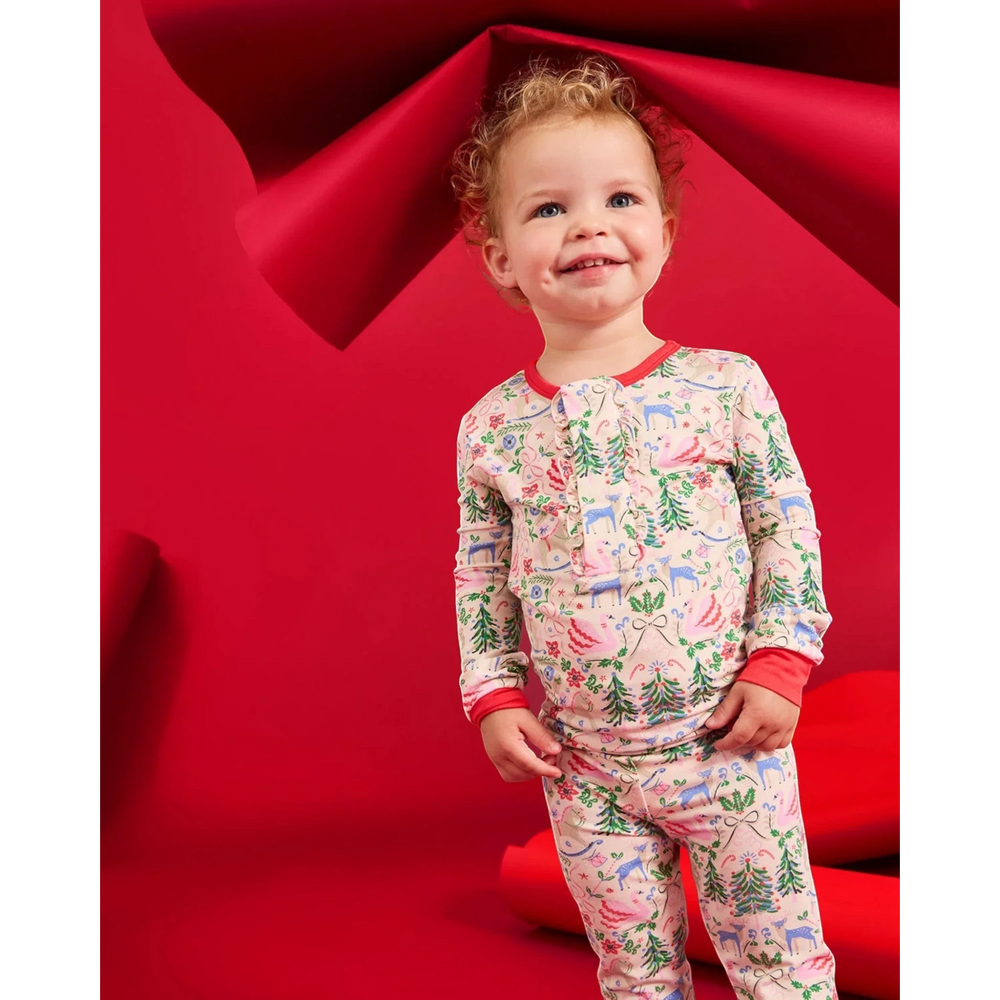 Toddler wearing That Store Sugar Plum Dreams modal long-sleeve pajama set with festive holiday print against red backdrop
