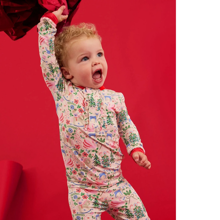 That Store toddler wearing a Sugar Plum Dreams modal long-sleeve pajama set with a festive floral and deer print.