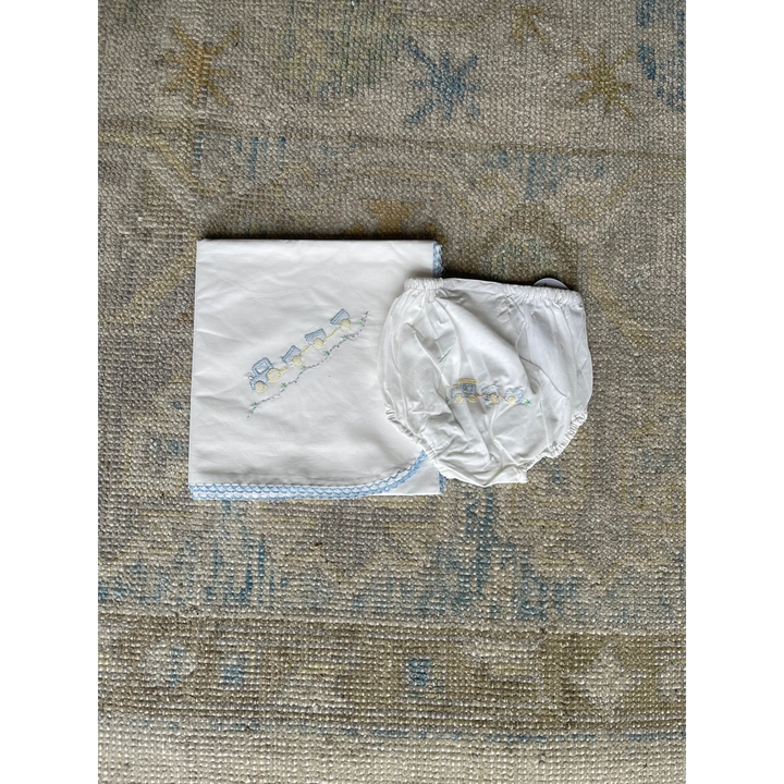 That Store white baby blanket and matching bloomer set featuring shadow stitched train embroidery and blue trim.