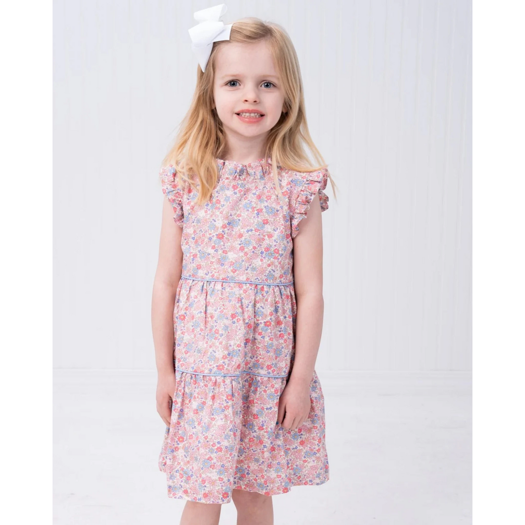 That Store Valeria pink and blue floral print dress with ruffle sleeves worn by a young girl with a white hair bow
