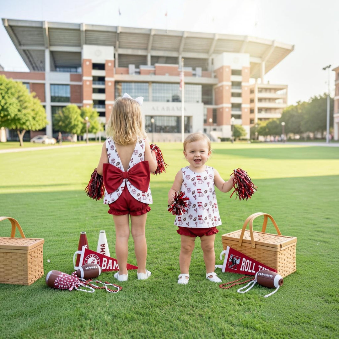 Two girls wearing That Store dark red and white patterned bloomer sets with back bows at a football stadium That Store