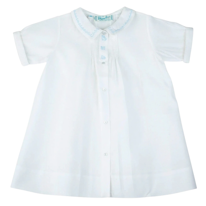 That Store white baby boy daygown with blue train embroidery, pintuck details, and a peter pan collar.