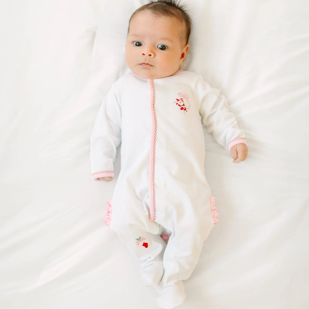 That Store baby footie in white cotton with pink picot trim, Santa embroidery, and back ruffles on a baby.