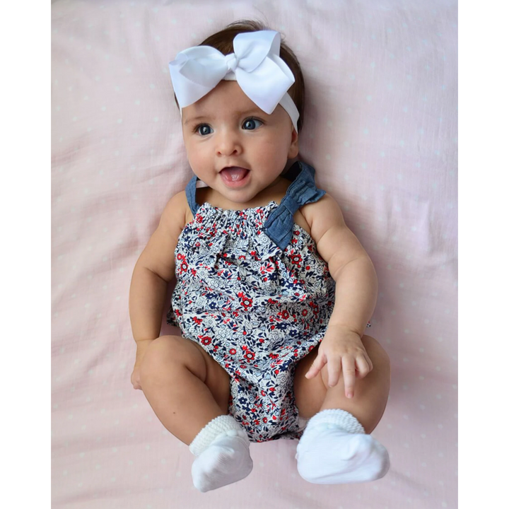 That Store baby wearing white cotton turn cuff socks with a bubble stitch design, paired with a floral romper