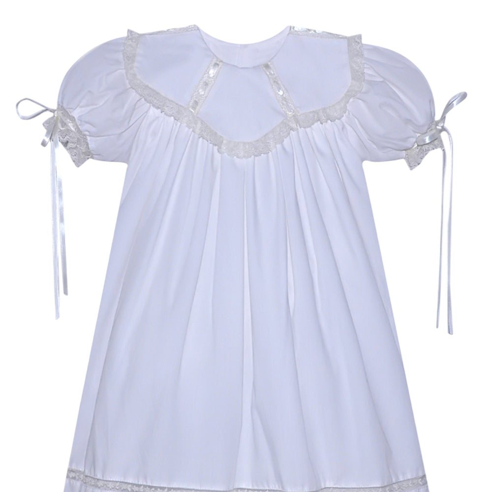 That Store white heirloom dress with ecru lace trim, puff sleeves, and ribbon ties for special occasions.