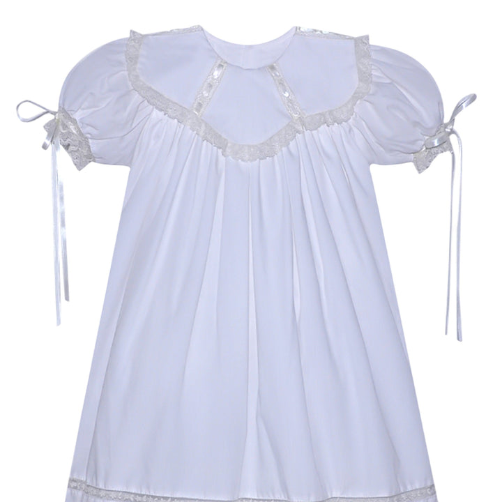 That Store white heirloom dress with ecru lace trim, puff sleeves, and ribbon ties for special occasions.