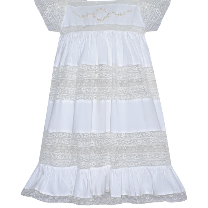 That Store white cotton heirloom dress featuring intricate lace panels and delicate floral embroidery on the bodice.