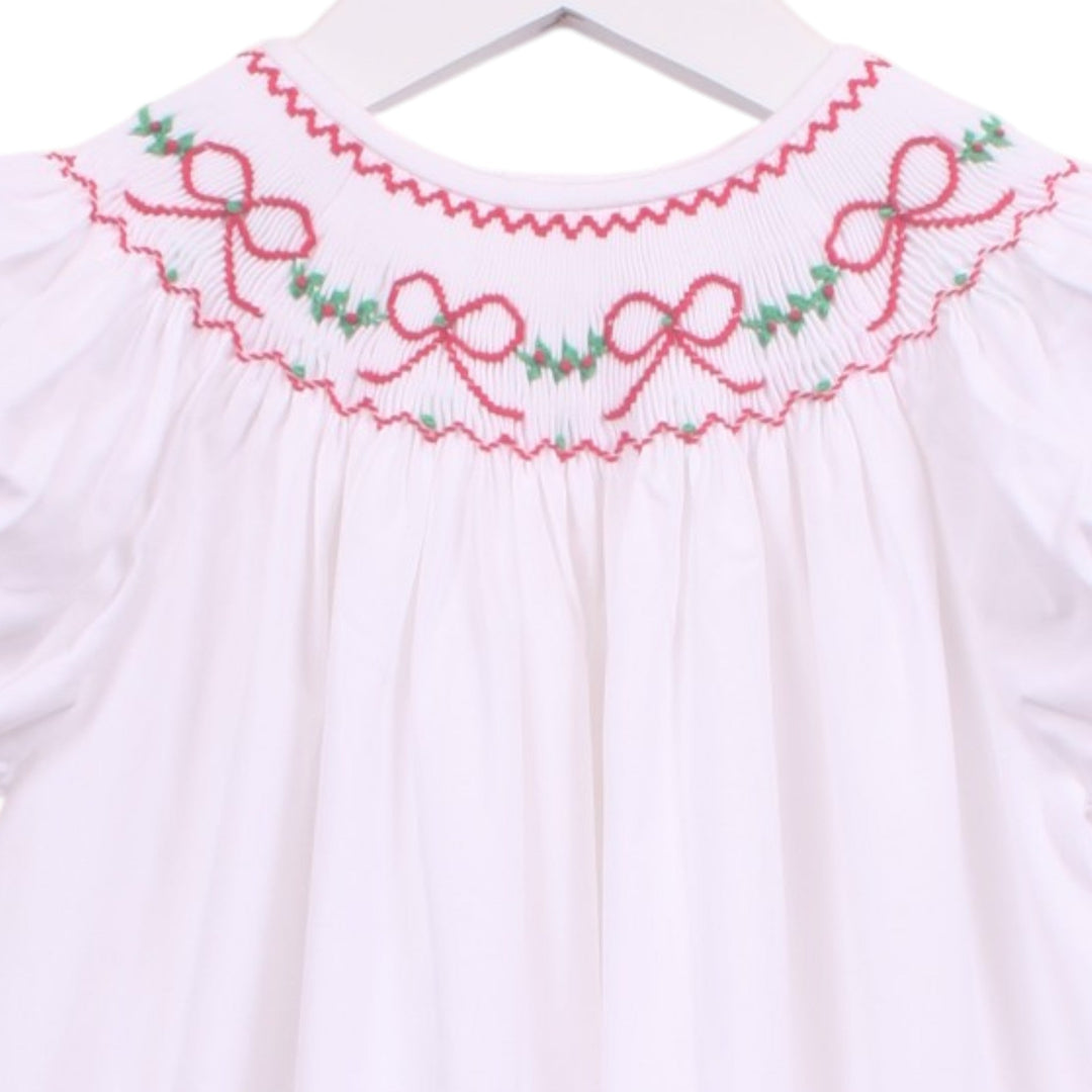 That Store white bishop dress with smocked neckline featuring red bows and green garland embroidery