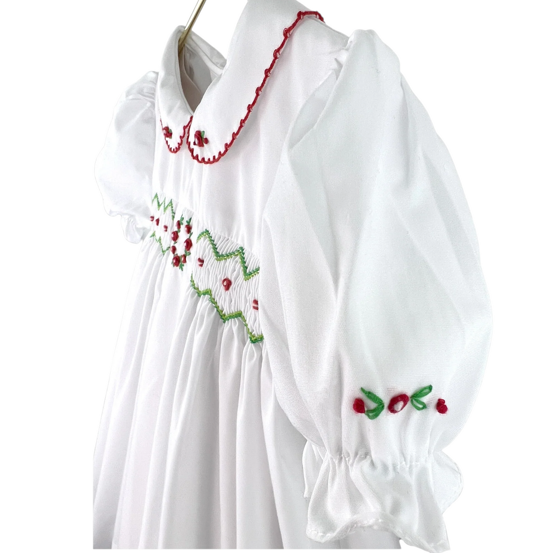 That Store white holiday dress for girls featuring red and green smocking, embroidery, and a peter pan collar.
