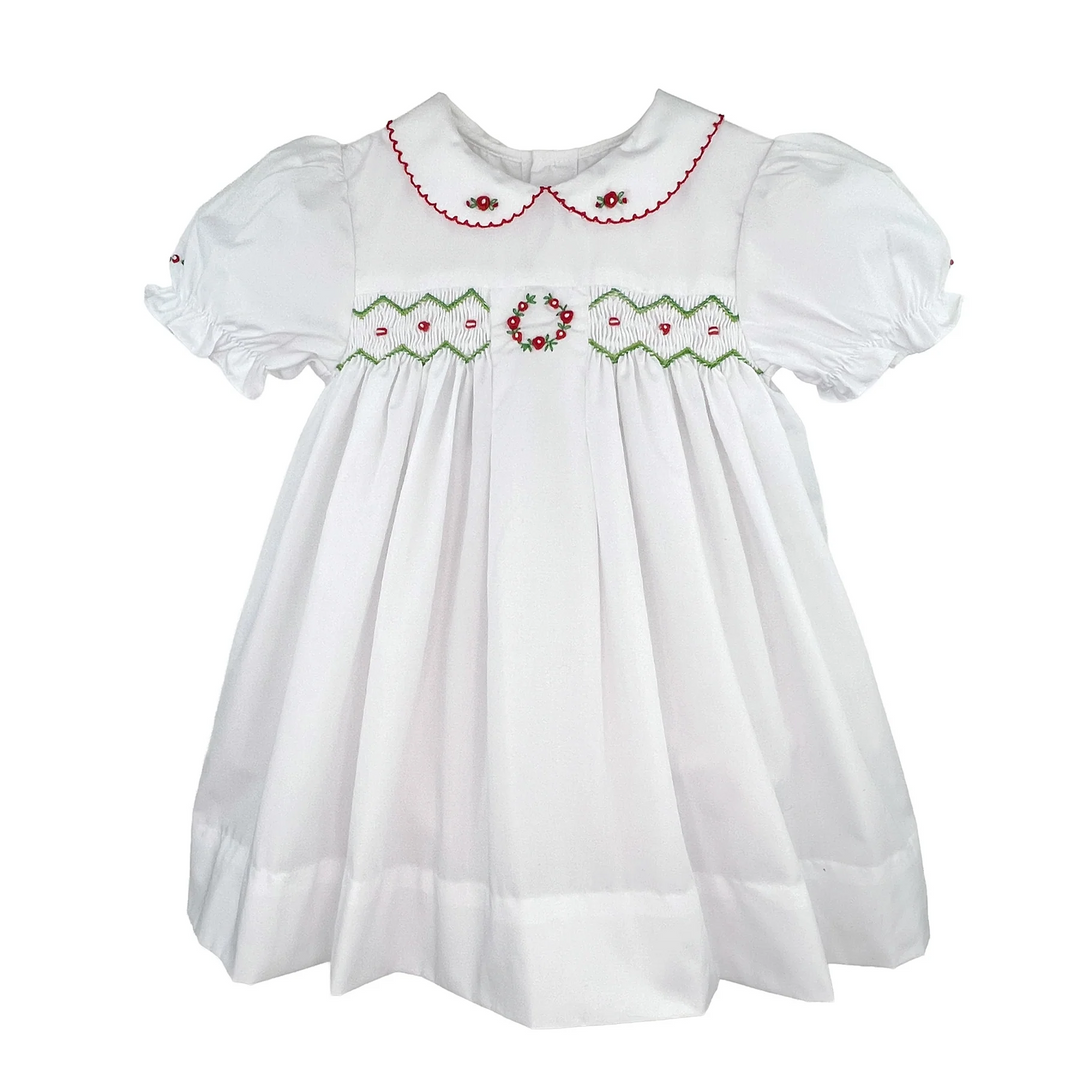 That Store white holiday dress for girls featuring red and green smocking, embroidery, and a scalloped collar.