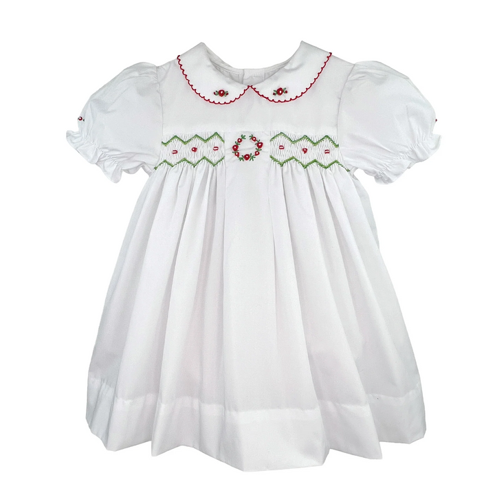 That Store white holiday dress for girls featuring red and green smocking, embroidery, and a scalloped collar.