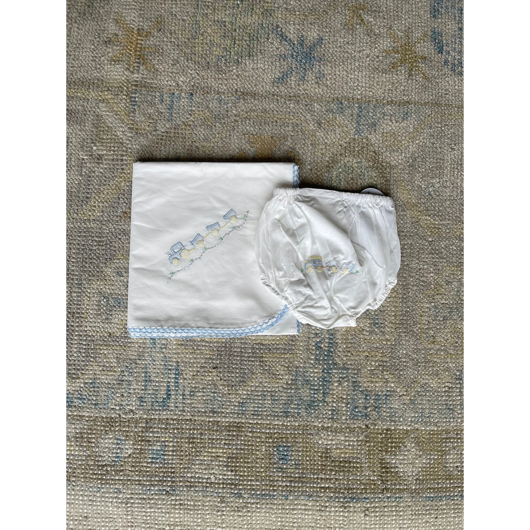 That Store white baby boy diaper cover and matching blanket featuring blue train embroidery and shadow stitching.