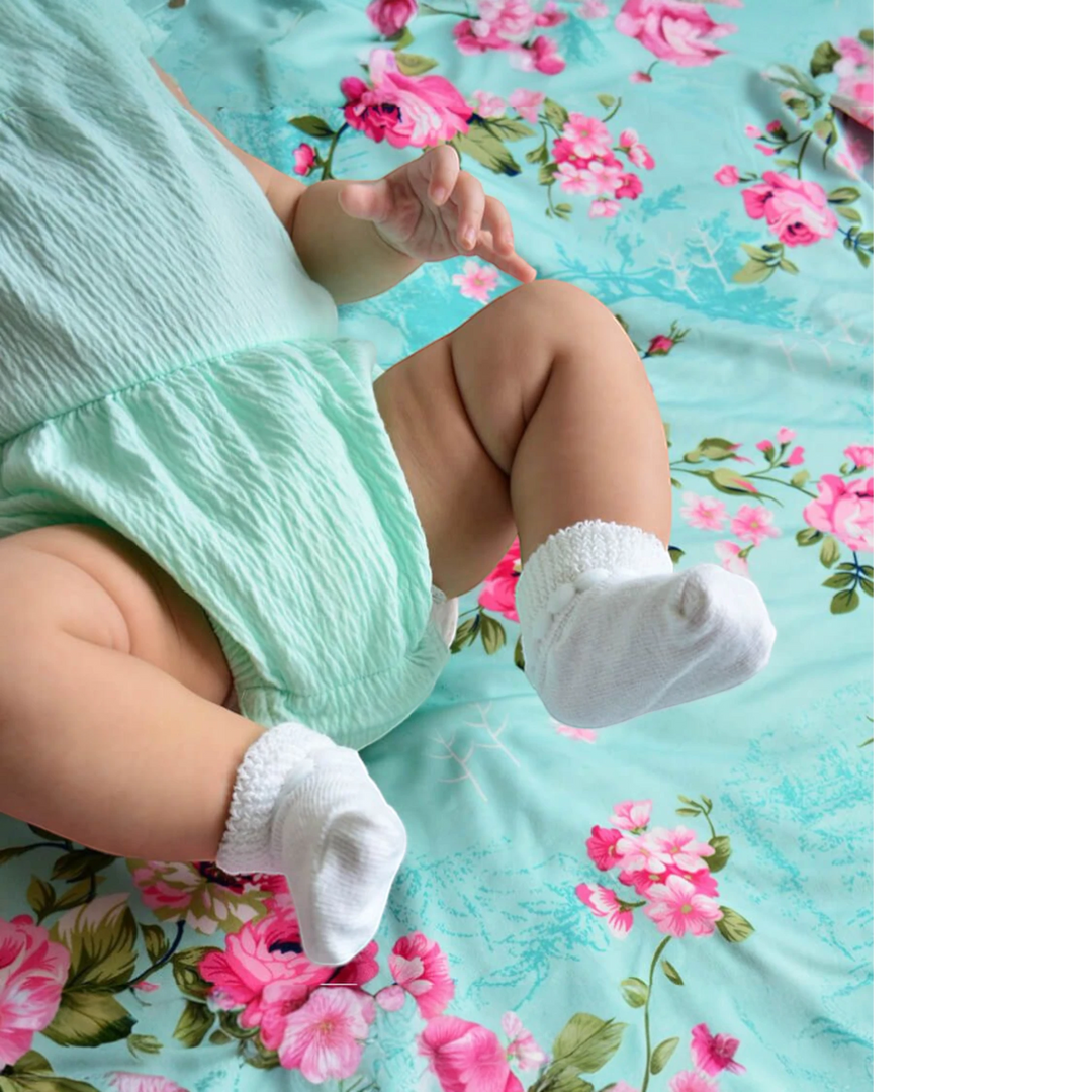 That Store white cotton turn cuff baby socks with bubble stitch detail worn by an infant on a floral blanket
