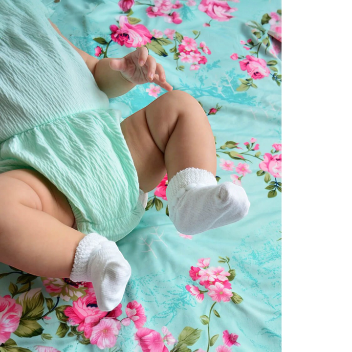 That Store white cotton turn cuff baby socks with bubble stitch detail worn by an infant on a floral blanket